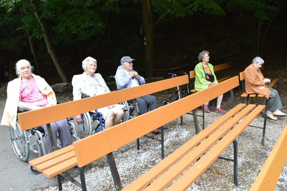 BewohnerInnen sitzen auf Bänken.